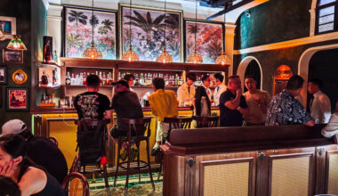 The interiors of Alma Luna cocktail bar showing a busy room against a cozy bar with tropical painting hanging above.
