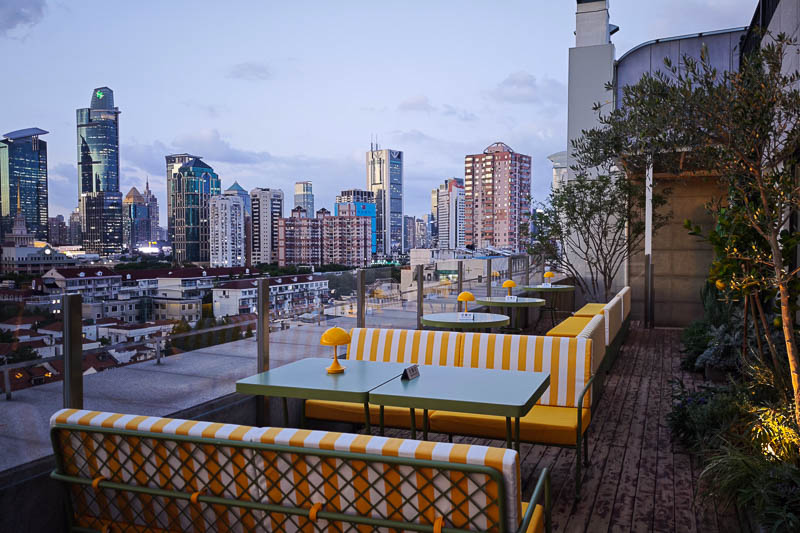The terrace at Bar Opia / Atelier Kaulou with outdoor lounge furniture and a downtown view of Shanghai