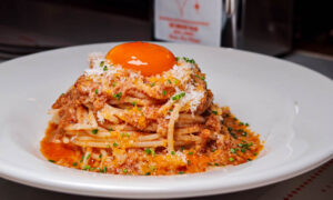 Spaghetti with tomato sauce topped with a bright yellow yolk