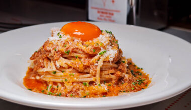 Spaghetti with tomato sauce topped with a bright yellow yolk