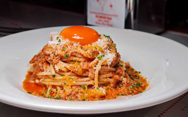 Spaghetti with tomato sauce topped with a bright yellow yolk